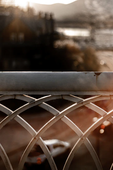 Close-up of a sleek black metal guardrail with intricate patterns glowing softly in evening light