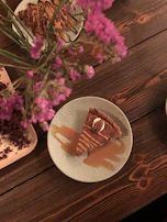 A decadent slice of pecan pie with a glossy caramel drizzle, styled on a black plate.