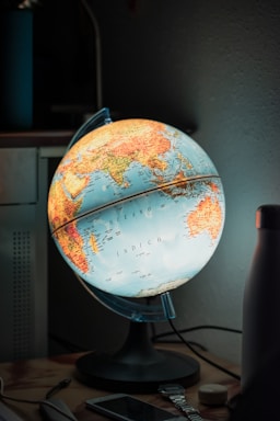 A compact smart gadget for travelers, glowing softly on a wooden table with travel maps around.