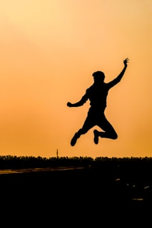 A vibrant photo of a person mid-jump during an outdoor workout at sunrise.
