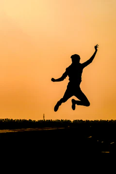 A vibrant photo of a person mid-jump during an outdoor workout at sunrise.