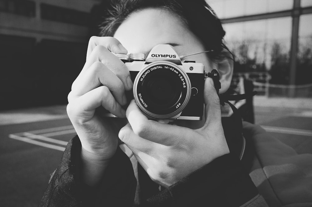 grayscale photography of woman holding DSLR camera