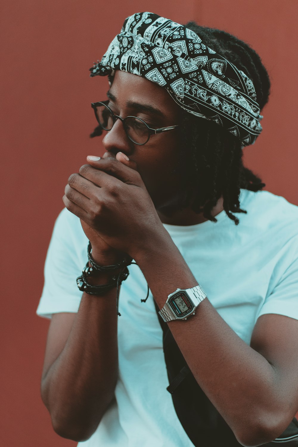 man wearing white crew-neck t-shirt covering mouth with both hands