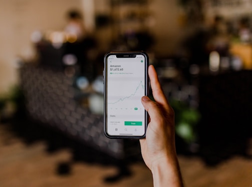 person holding black iPhone displaying stock exchange