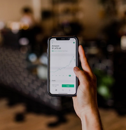 person holding black iPhone displaying stock exchange