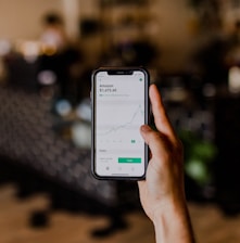 person holding black iPhone displaying stock exchange