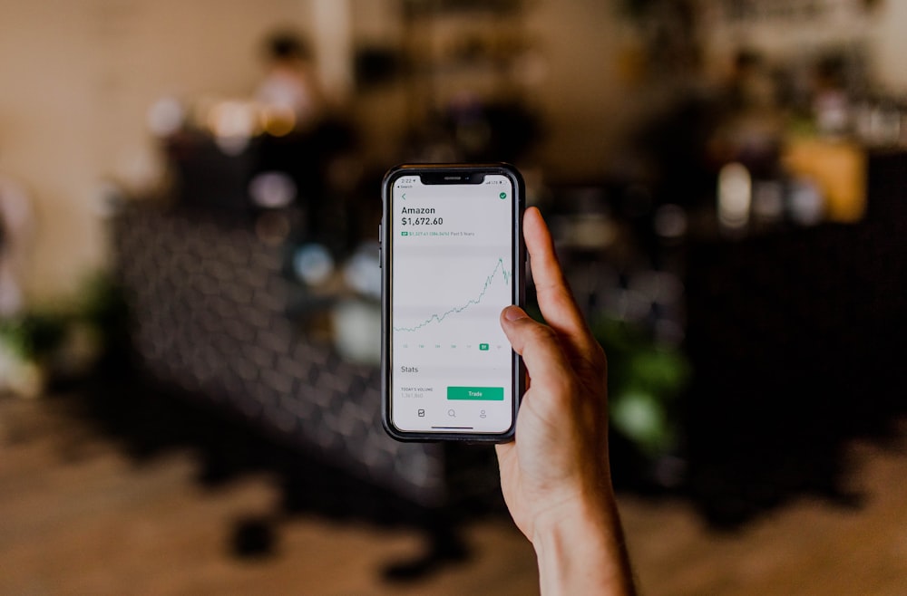 person holding black iPhone displaying stock exchange