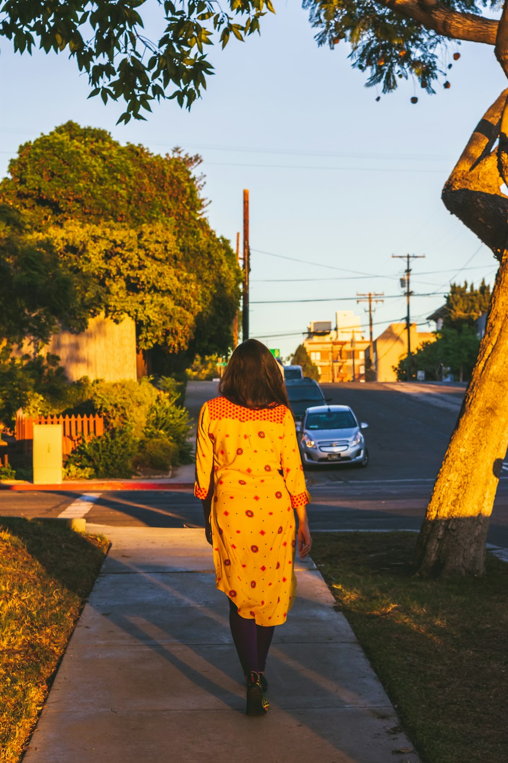 woman in orange dress walking on pathway during golden hour