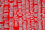 Silver nameplate necklaces are displayed against a vibrant red background. Each necklace is pinned individually and features a variety of names in a cursive style.