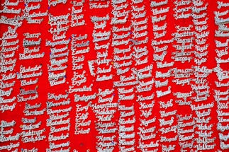 Silver nameplate necklaces are displayed against a vibrant red background. Each necklace is pinned individually and features a variety of names in a cursive style.