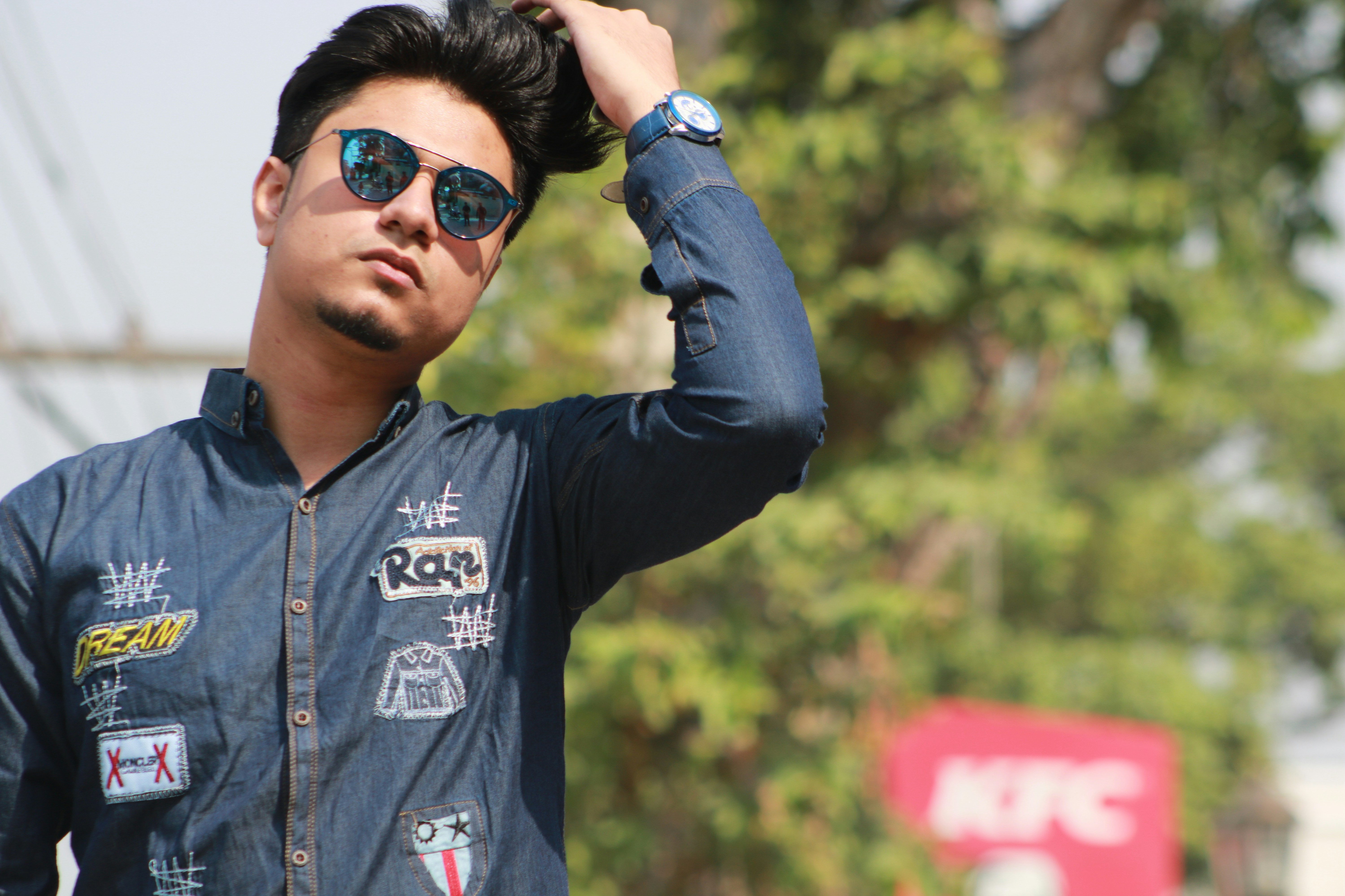Pria mengenakan jaket denim biru berdiri dan menyentuh rambutnya