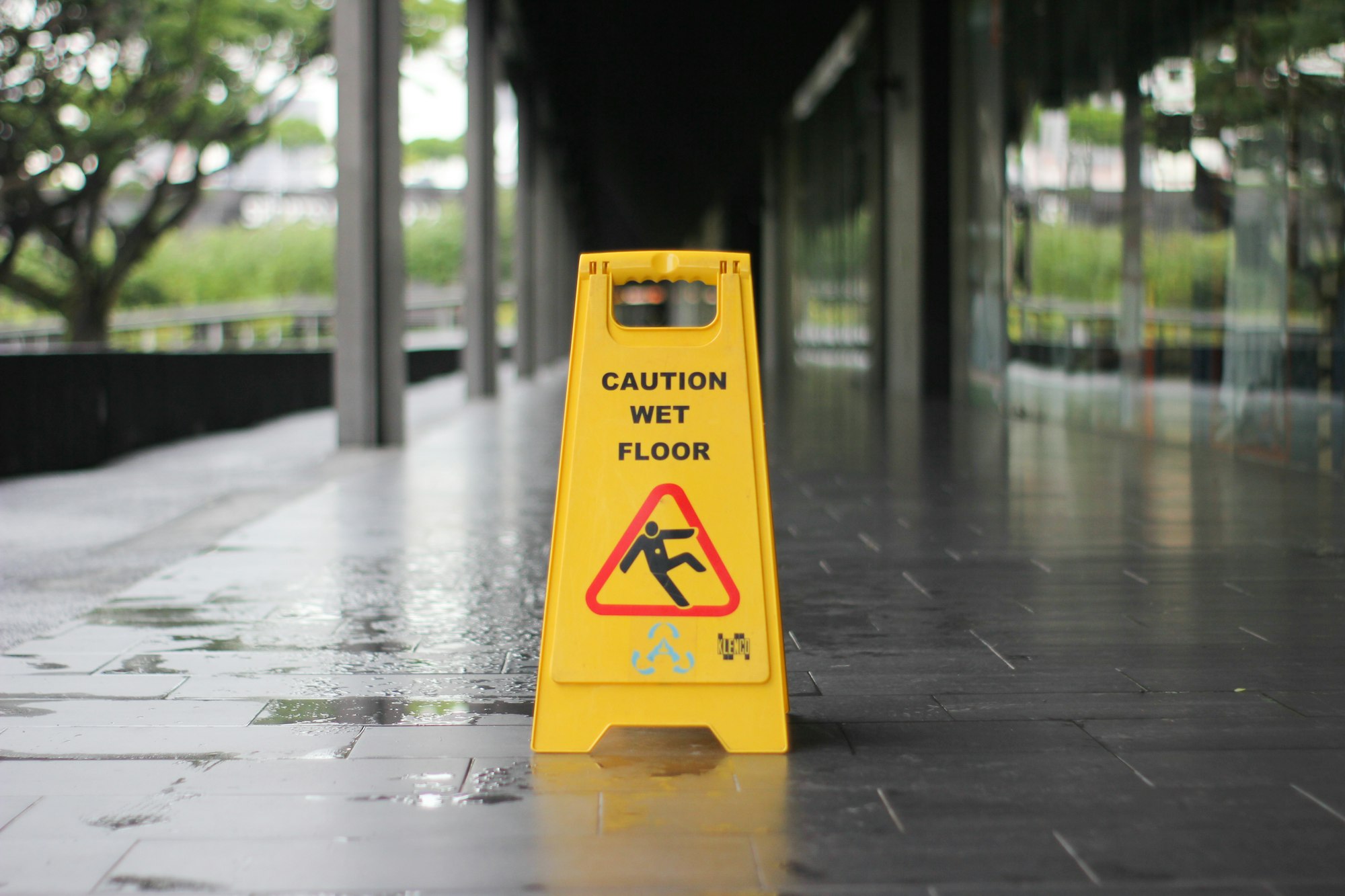 yellow Caution wet floor signage on wet pavement