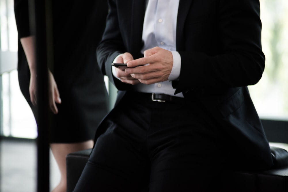 man in black suit with phone in hand