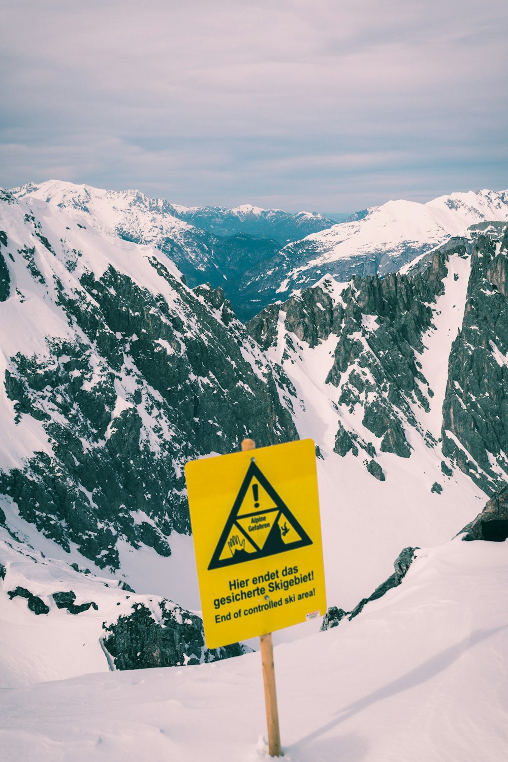 Gelb-schwarzes Schild auf schneebedecktem Berg