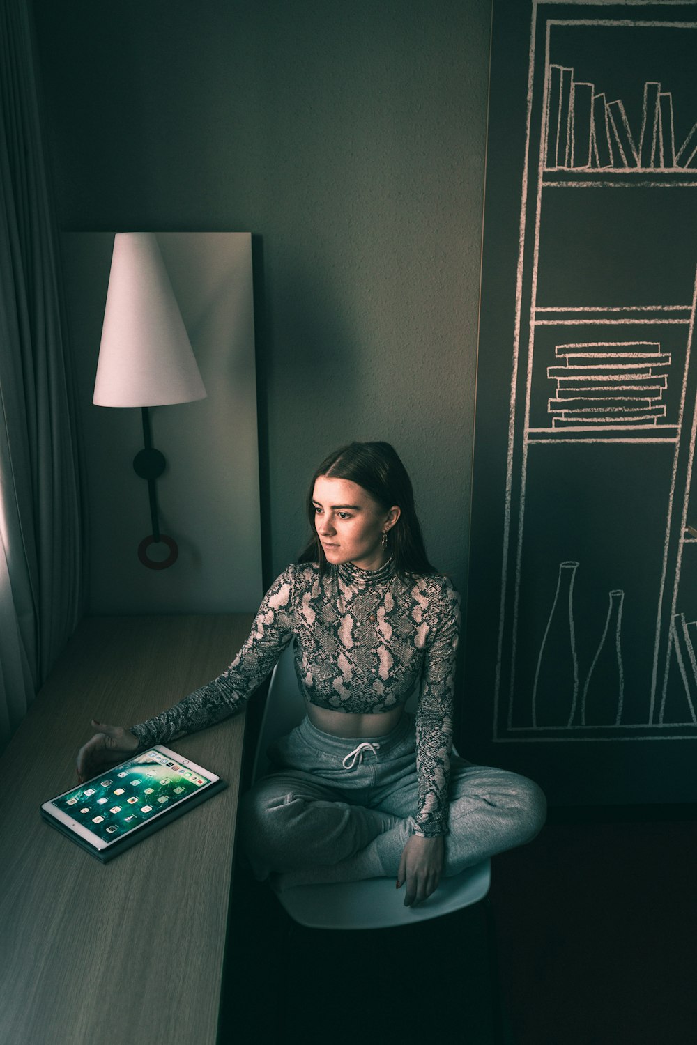 sitting woman sitting beside chair with turned-on tablet computer