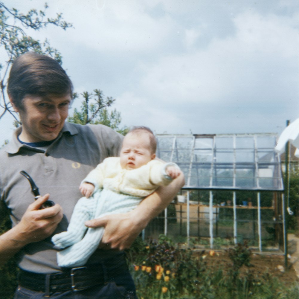 man in grey polo shirt holding baby