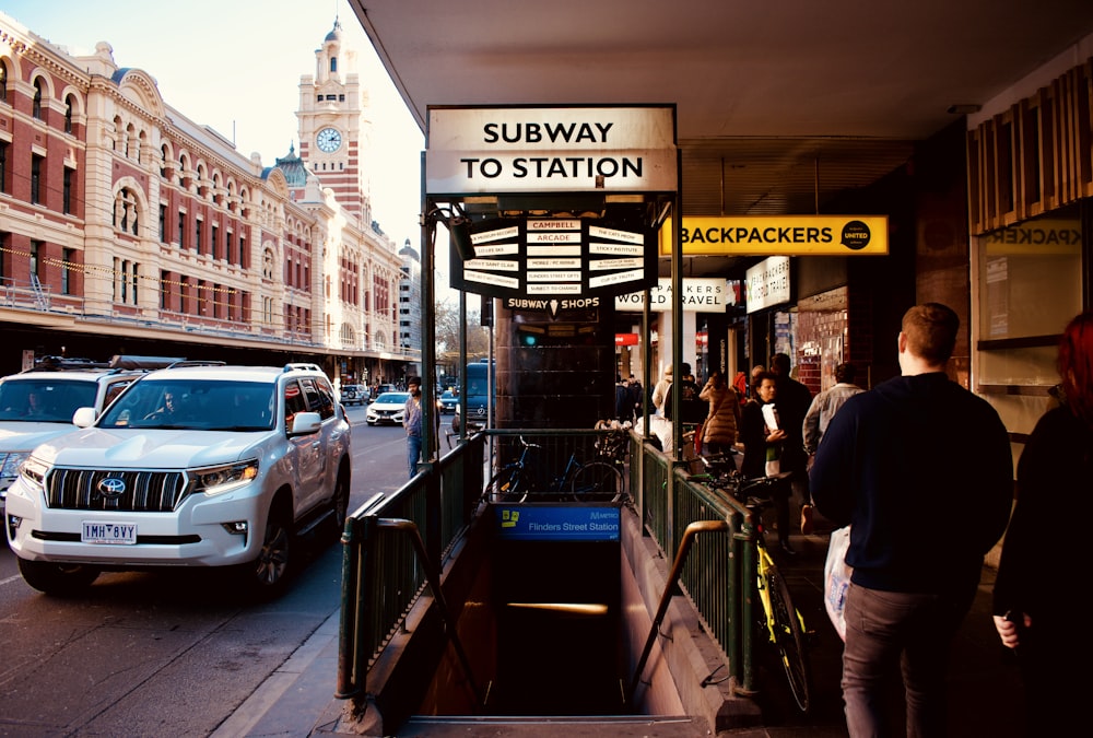 people walking on sidewalk with subway station stairs