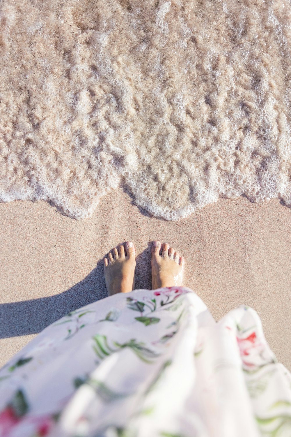 Donna che indossa il vestito floreale bianco in piedi vicino allo specchio d'acqua