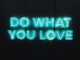 Neon blue letters spelling out 'DO WHAT YOU LOVE' against a dark background, creating a vibrant and motivational atmosphere.