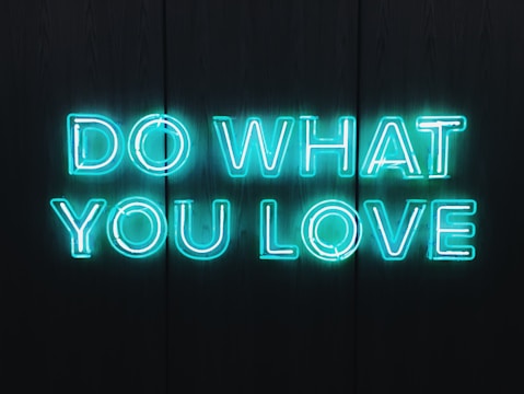 Neon blue letters spelling out 'DO WHAT YOU LOVE' against a dark background, creating a vibrant and motivational atmosphere.