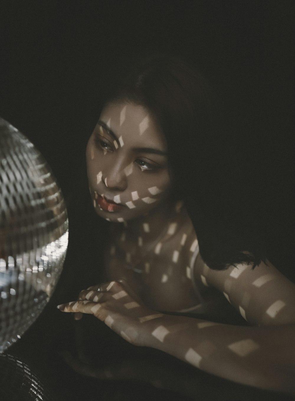 a woman with her hands on her chest in front of a disco ball