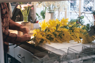 A cheerful florist arranging a bouquet in a bright, cozy workshop.