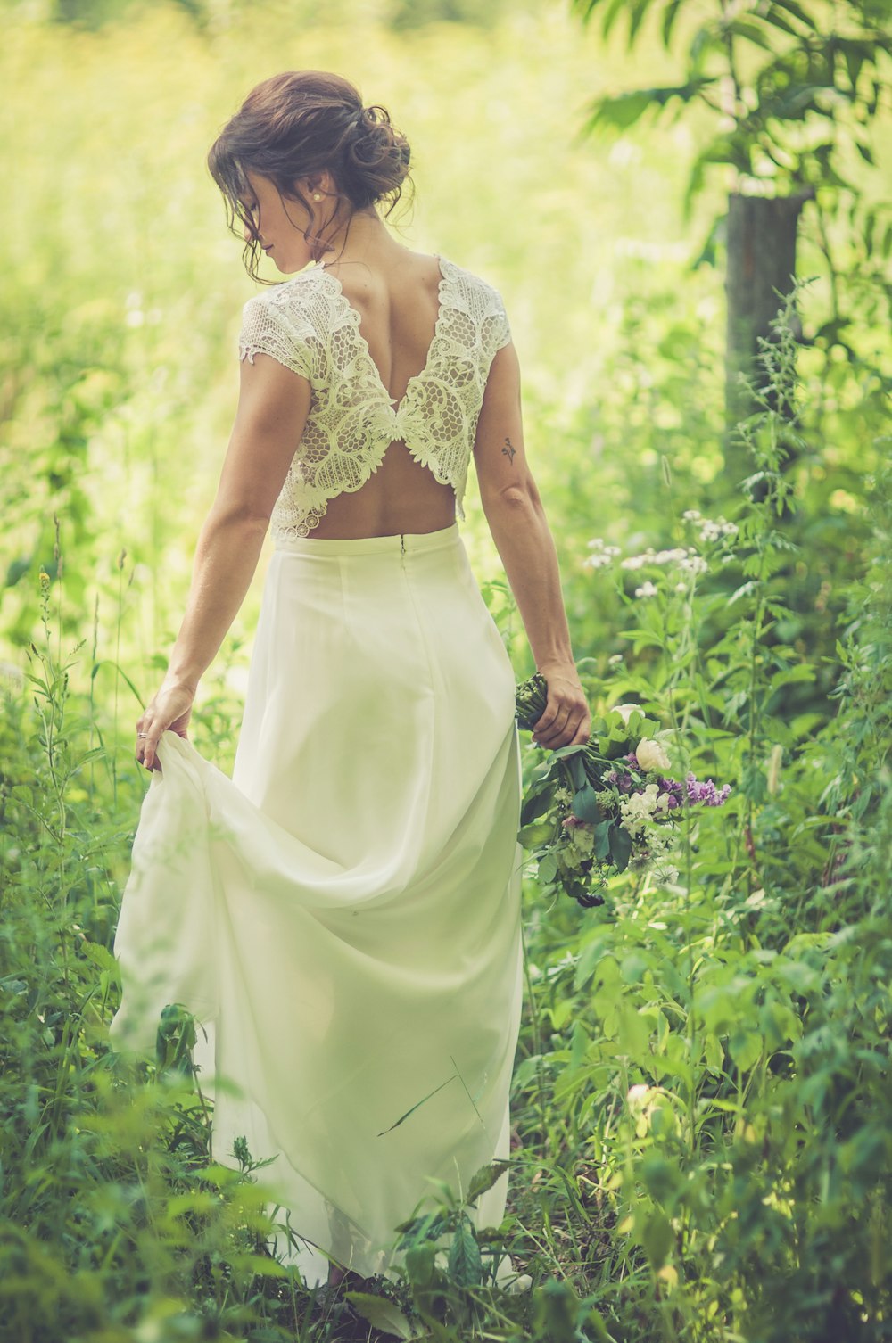 woman in white dress holding bouquet while standing on field