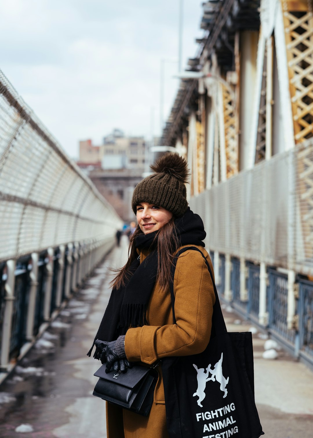 woman in brown bobble hat and orange coat carrying tote bag