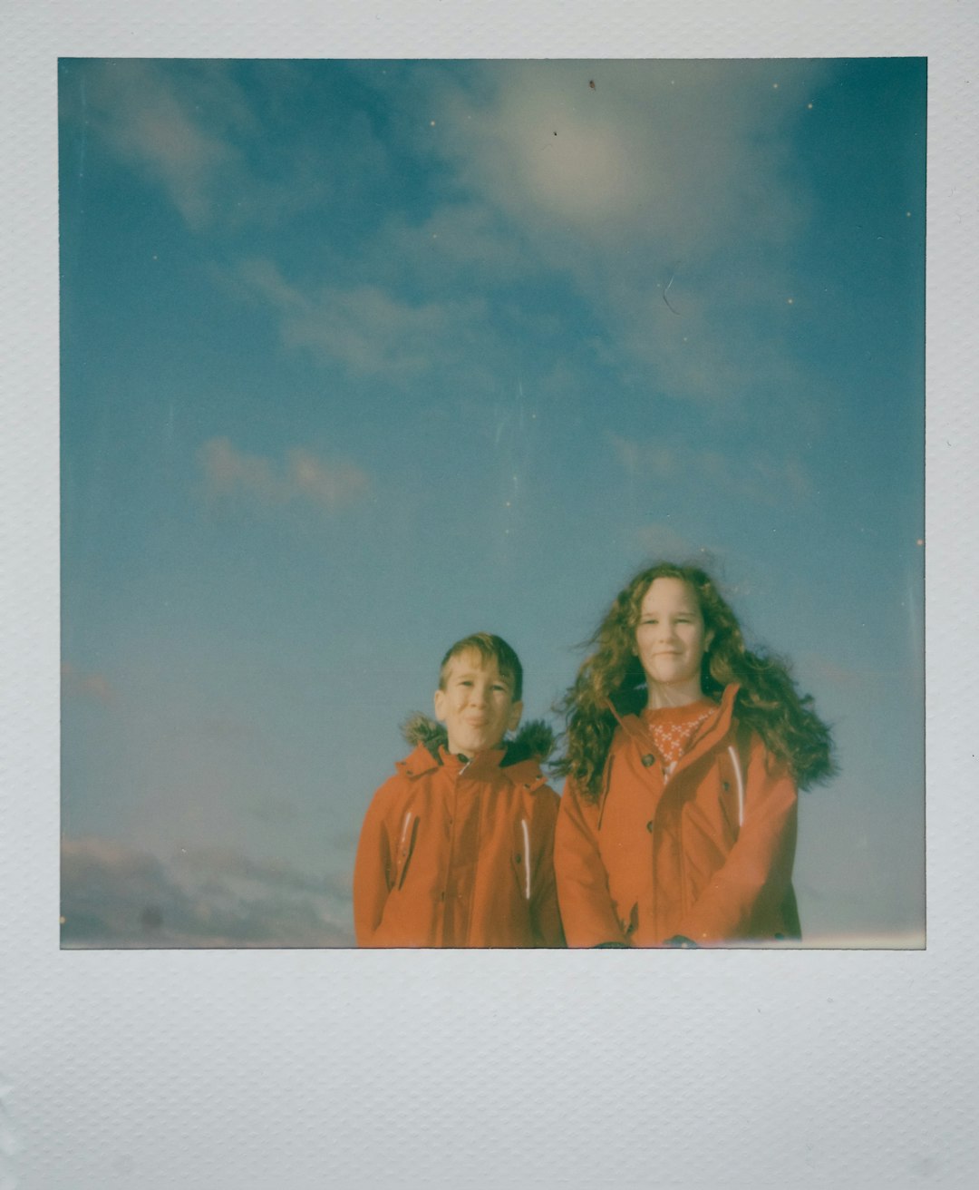 girl and boy wearing orange jackets standing
