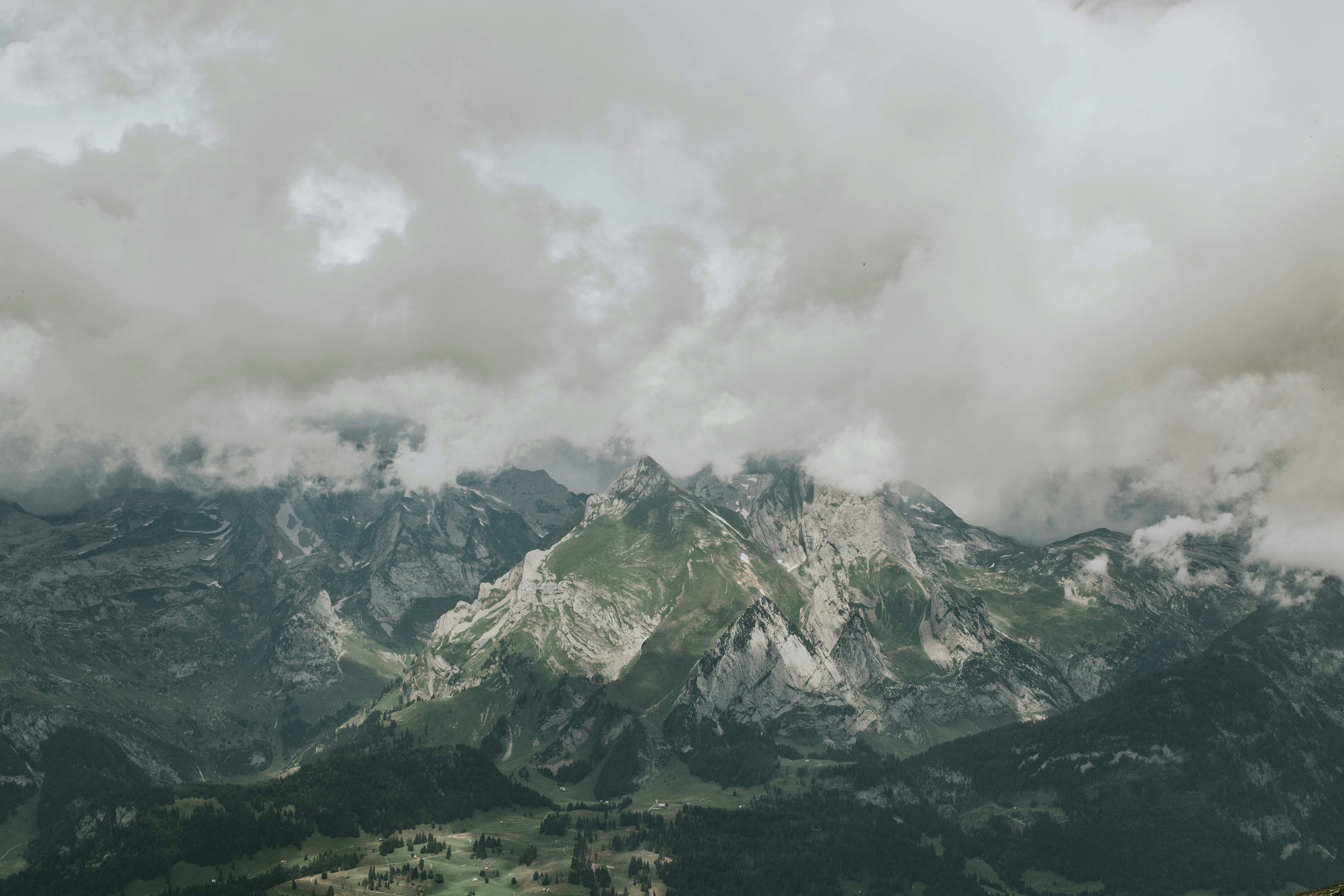 white clouds above green and grey mountains, 