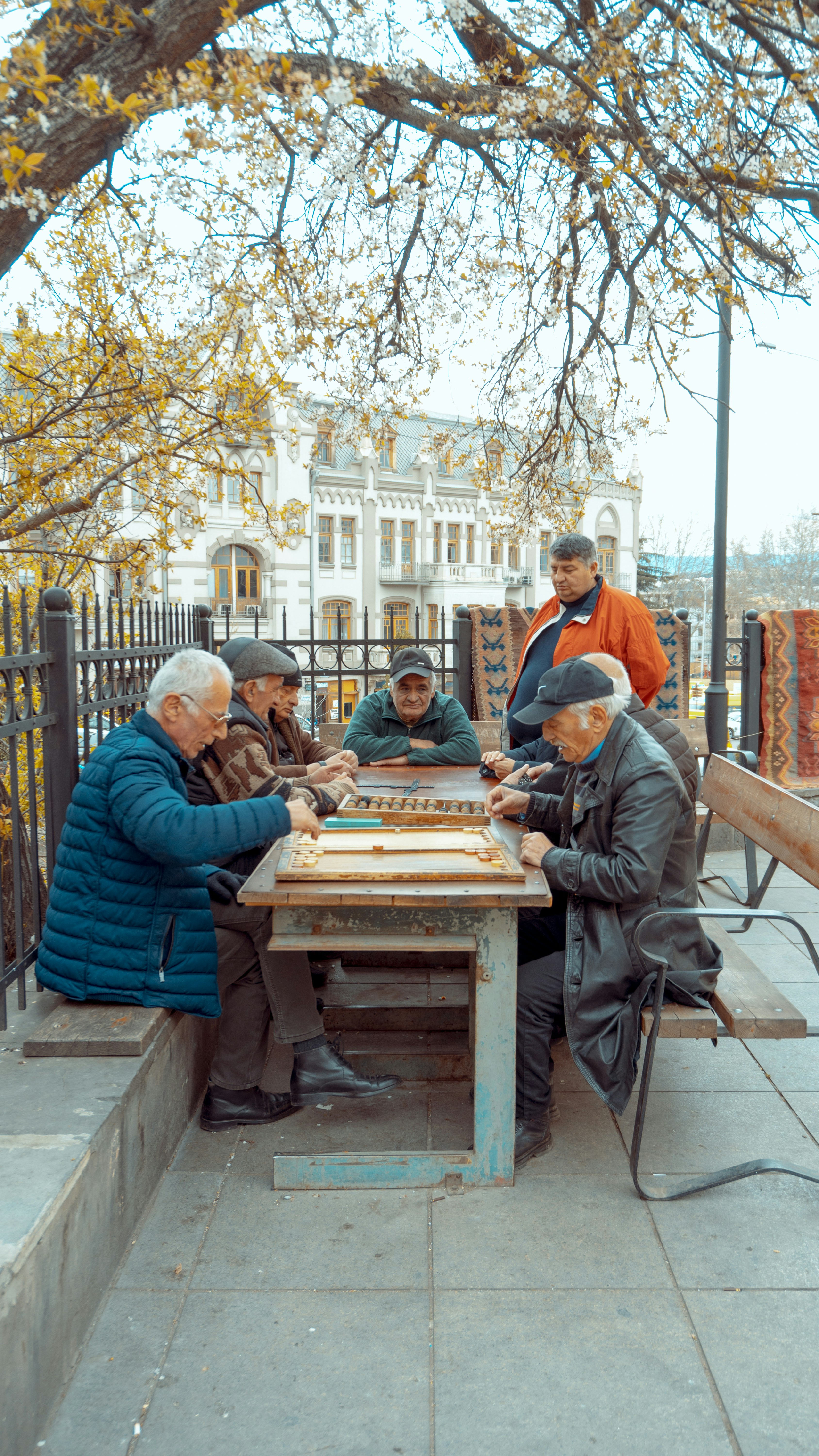 group of men sitting beside table under yellow leafed tree