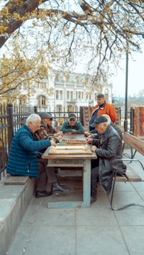A group of elderly people engaged in a memory game around a table, smiling and focused.
