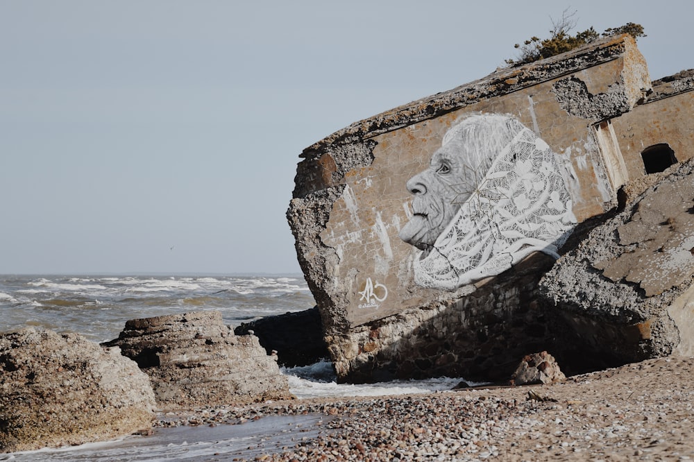 white woman with shawl drawing on concrete block in beach