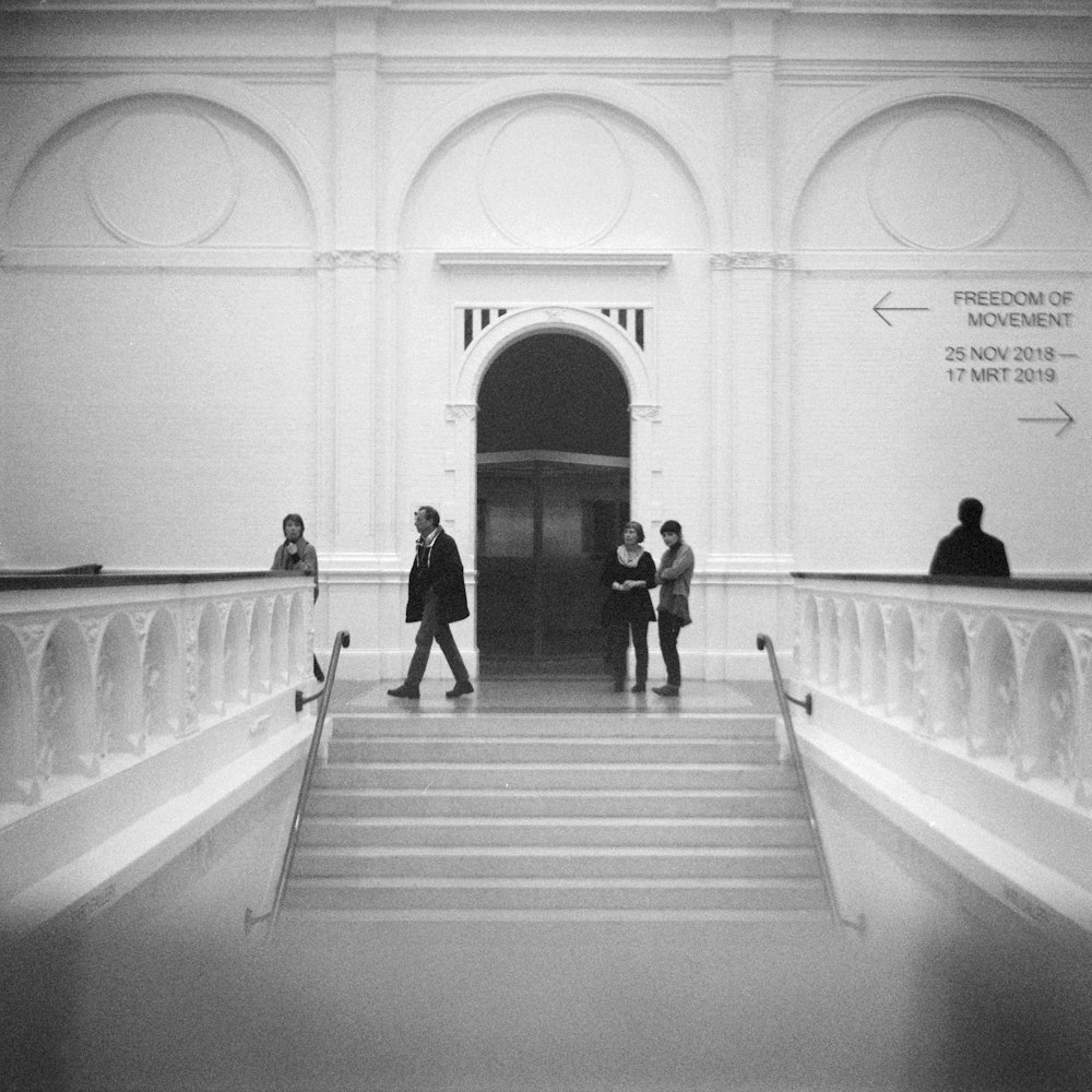 people walking near door with stairs in front inside building