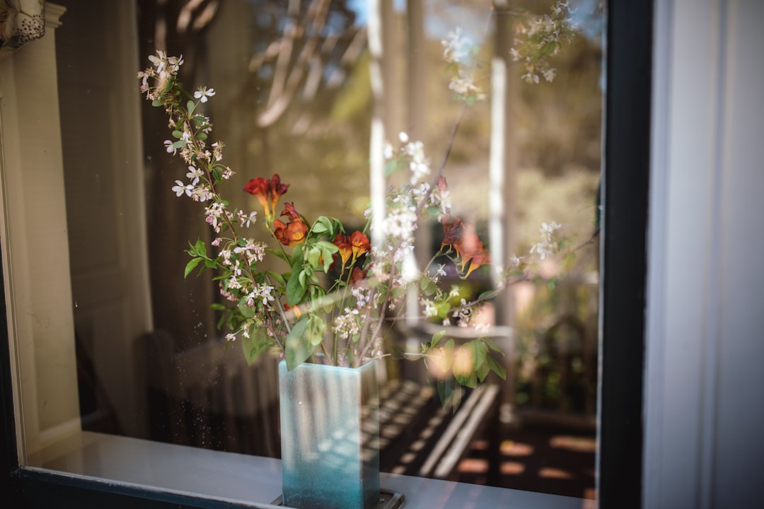 flowers in vase behind clear glass window
