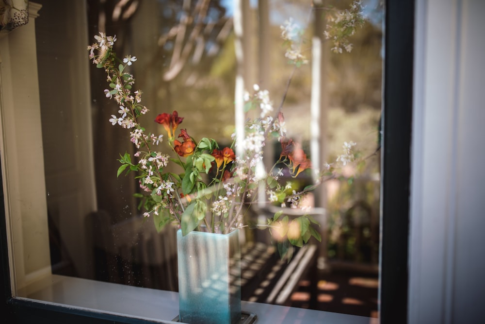 flowers in vase behind clear glass window