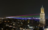A vibrant drone light show illuminating the night sky over a cityscape.