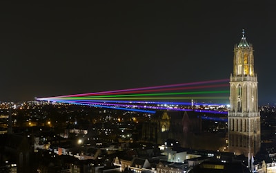 Colorful drone light show illuminating a night sky over a city plaza.