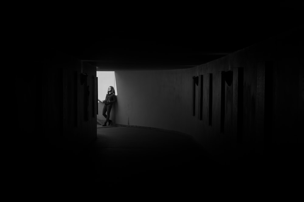 grayscale photography of man leaning on wall