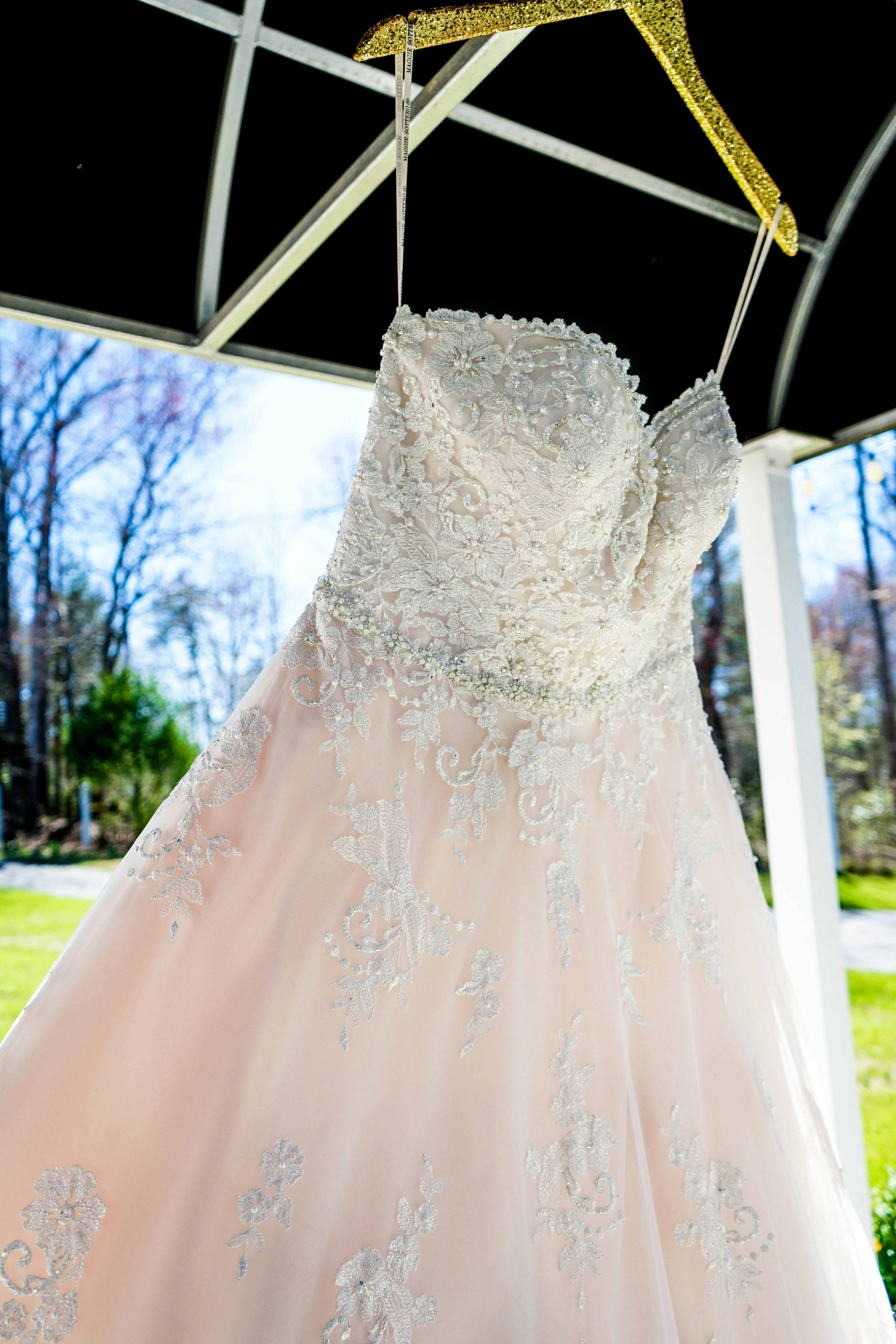 white floral sweetheart wedding gown hanging inside gazebo