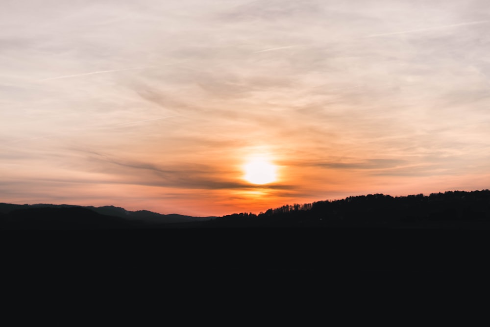 the sun is setting over a mountain range