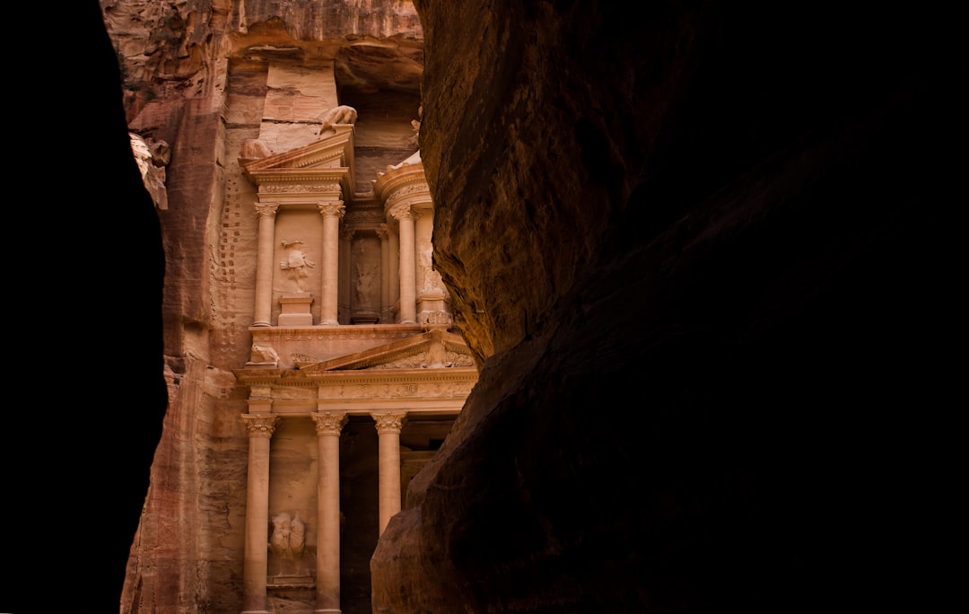 low angle photography of rock formation, Petra treasure ancient architecture building inside canyon dark rock walls fram