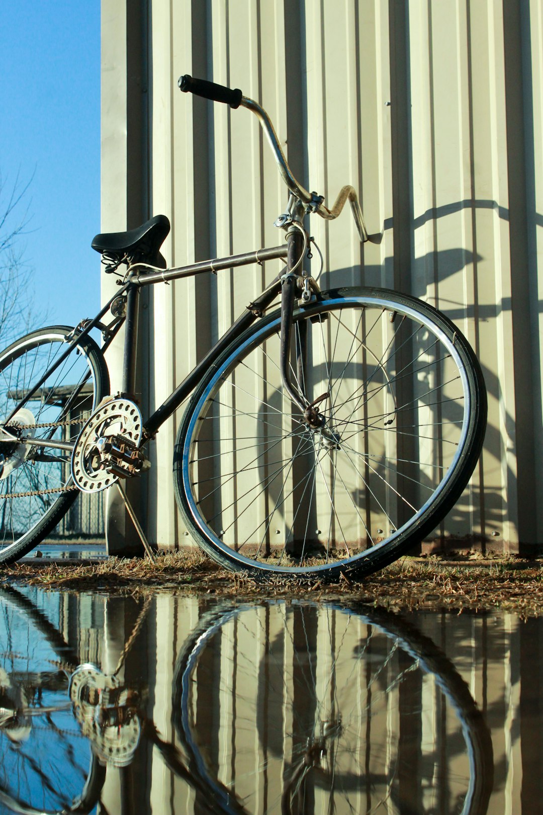 bicycle leaning on wall with reflection on water