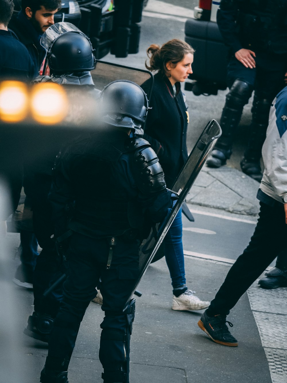 woman walking in front of two men carrying shields