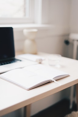 A clean desk with a laptop and a notepad for communication.