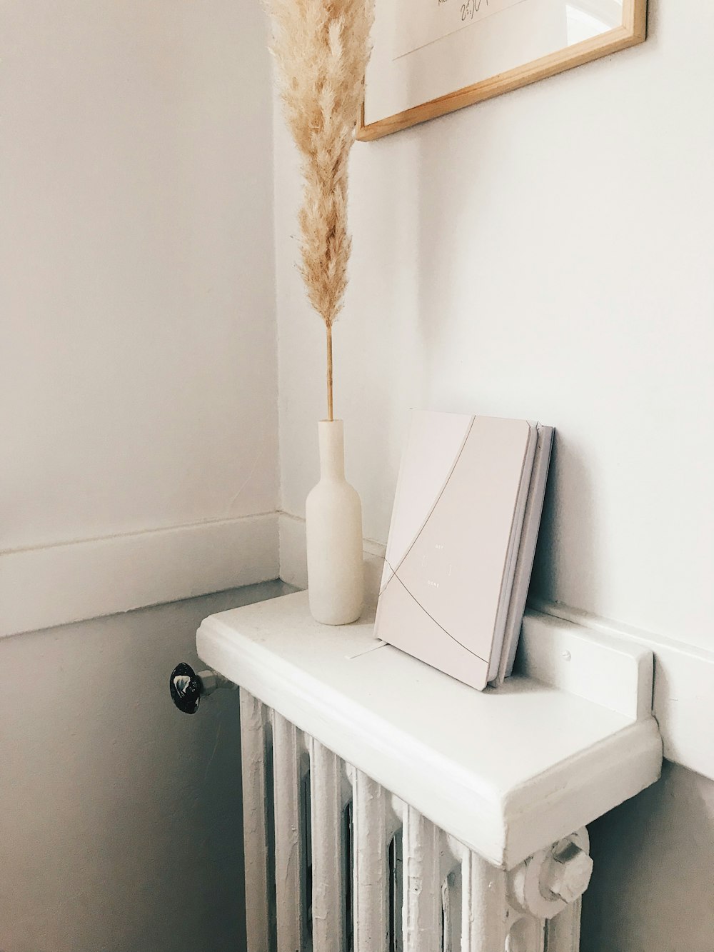 a white radiator with a vase and a feather on top of it