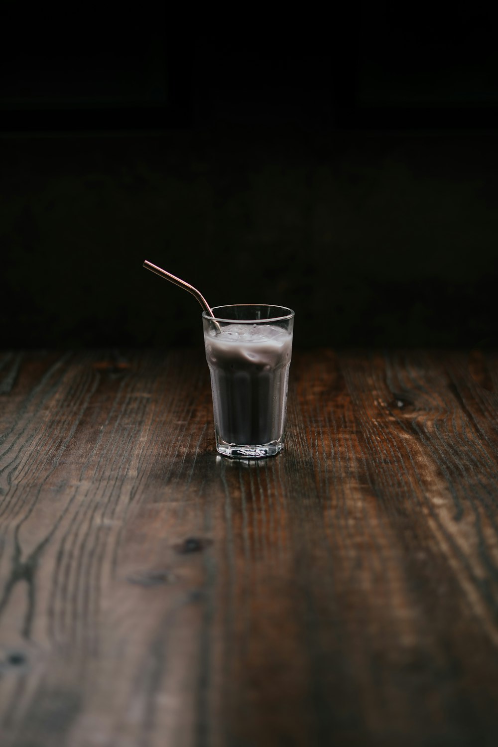 clear drinking glass with shake and straw on table