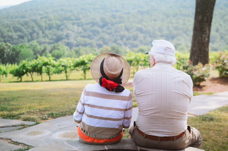 An older couple sitting together on a pathway