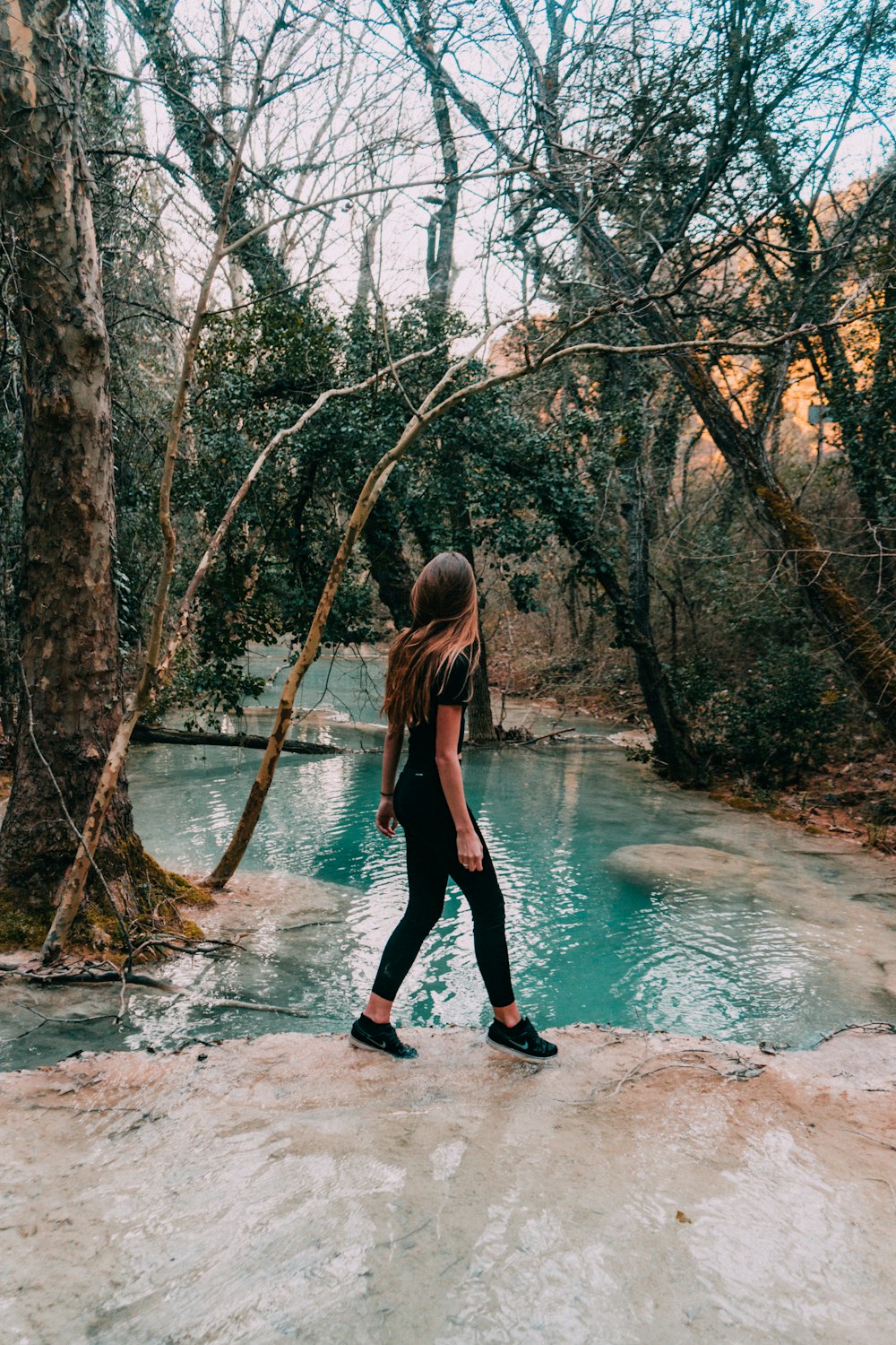 woman wearing black shirt walking on lake