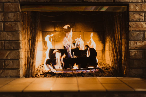 Burning logs and warm flames in a stone-lined fireplace.